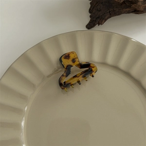 Detailed close-up of a large tortoiseshell hair claw clip on a wavy ceramic plate