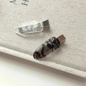 Close-up of black and white lace print hair clips with silver metal duckbill base