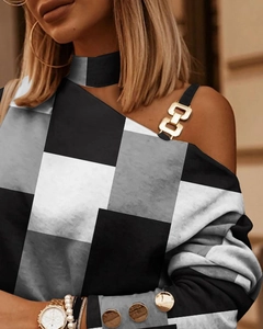 Detalle de hebilla metálica y botones dorados en blusa de cuadros con manga larga