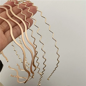 Handheld display of various wavy gold metal headbands with minimalist aesthetic