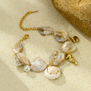 Detail shot of marine style bracelet with natural shell and pearl on beach stone