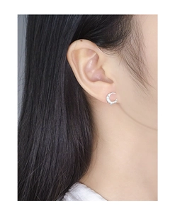 Macro shot of silver crescent moon stud earring with textured surface on female model