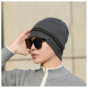 Detail of grey winter knit beanie with black stripes and brand label on outdoor model