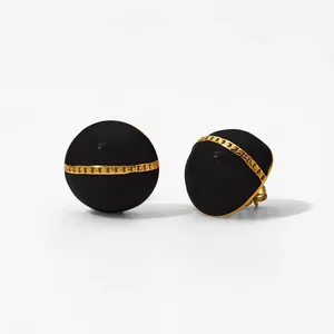 Detail of round black enamel stud earrings with gold chain link motif in macro view