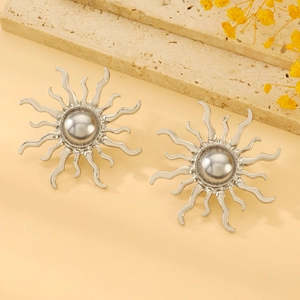 Detail of silver sunflower earrings with central pearl on a stylish marble display