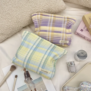 Close-up of checkered fabric makeup bags with stitched brand labels in a cozy setting