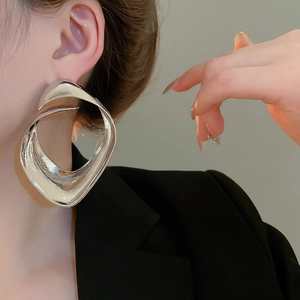 Primo piano di modella che indossa grandi orecchini geometrici in argento lucido
