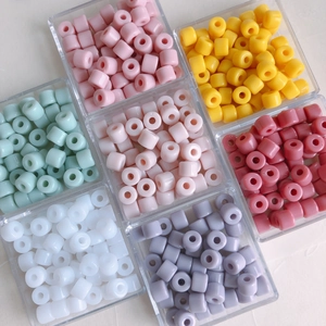 Colorful cylindrical acrylic spacer beads neatly arranged in a transparent storage box