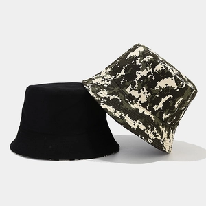 Detailed view of reversible bucket hats in solid black and green digital camo canvas