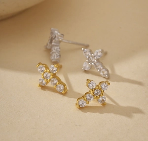 Macro shot of silver and gold S925 cross stud earrings with sparkling zircon inlay