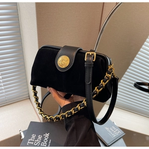Detail of vintage black crossbody bag with gold embossed buckle and woven chain strap