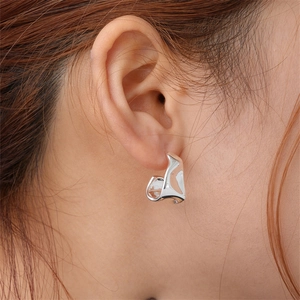 Macro shot of silver liquid metal earring with an irregular flowing design on ear