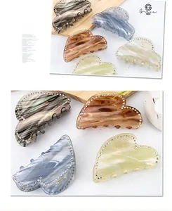 Macro detail of heart-shaped acetate hair claw clips with marble texture and rhinestones