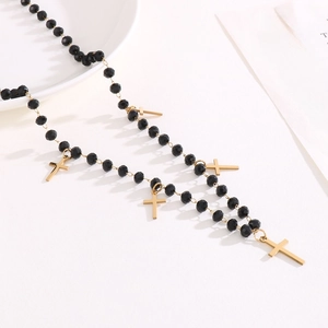 Elegant beaded necklace with black crystals and golden cross charms on white decor