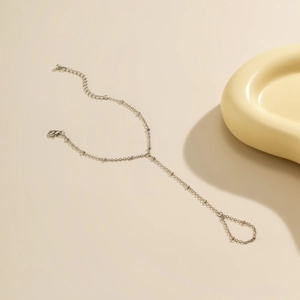 Detail of silver chain bracelet with faux pearls and finger ring on a minimal background