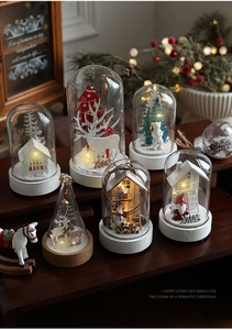 Detail of Christmas glass dome with miniature reindeer and cabin on a wooden shelf