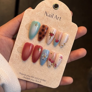 Close-up of handmade press-on nails with 3D cherry, floral reliefs, and blue-red gradient