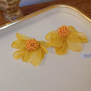 Detailed close-up of yellow organza petal earrings with handcrafted seed bead centers