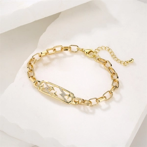 Detailed view of gold plated star and lightning bolt bracelet on white marble texture