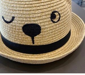 Close-up of woven straw texture and cute animal embroidery on baby sun hat