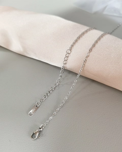 Close-up of silver stainless steel chain with lobster clasp on beige silk roll