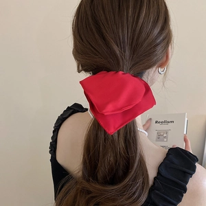 Elegant red satin bow hair tie worn on a ponytail for a sophisticated look