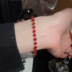 Detailed macro view of an 18k gold ruby bracelet featuring square cut crystals on a wrist