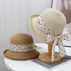 French style sun hat with polka dot bow and metal tag on woven straw texture