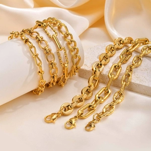 18K gold plated stainless steel Figaro chain bracelets on elegant white stone display