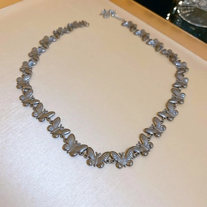 Detailed view of a silver butterfly pendant necklace resting on a beige jewelry display tray