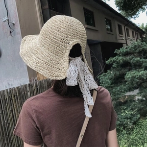 Cappello di paglia da donna con fiocco in pizzo bianco e tesa larga vista da dietro