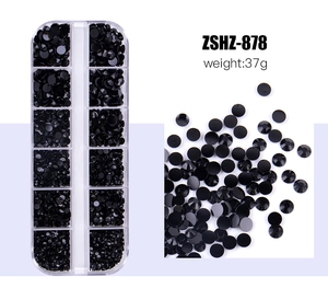 Detailed view of black flatback rhinestones in a 12-grid storage box for DIY nail art