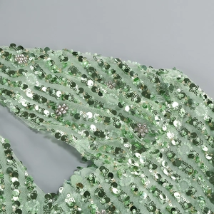 Macro detail of mint green dress featuring sequins and silver rhinestone floral embroidery