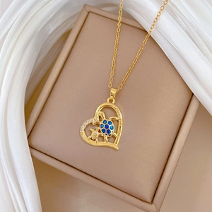 Close-up of golden heart necklace with blue tortoise pendants on beige jewelry box