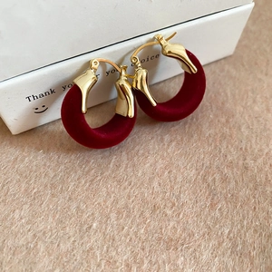 Detail of vintage red flocked U-shape earrings with gold metallic finish and velvet texture