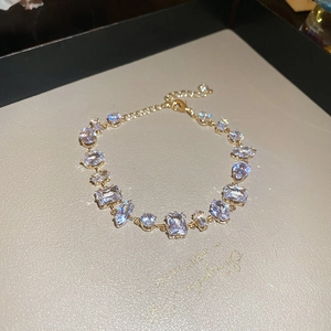 Detail of adjustable gold bracelet with various cut clear crystals and lobster clasp