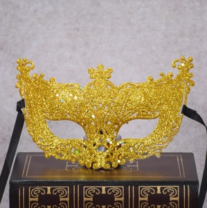 Glittery gold Venetian lace mask with intricate cutout design and black ribbons
