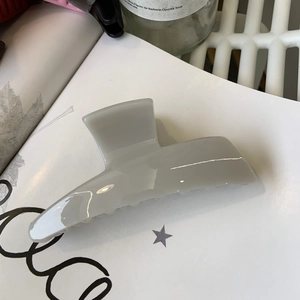 Detailed view of the large glossy grey hair claw clip on a minimalist white background