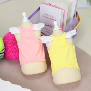Pink and yellow knit pet vests with white lace straps shown on a decorative table