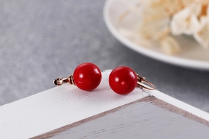 Vue macro de boucles d'oreilles pendantes à perles rouges avec monture en or rose poli