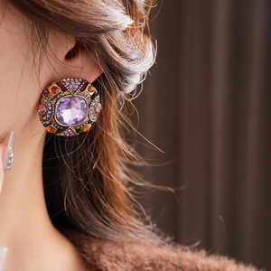 Macro detail of vintage bronze earrings with purple gemstone and crystals on model