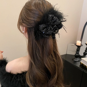 Detail of a large black feather hair claw clip with sequins on a model's hair