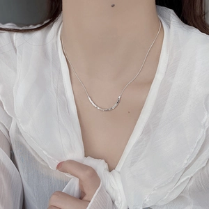 Close-up of minimalist 925 sterling silver geometric cube necklace on model neck