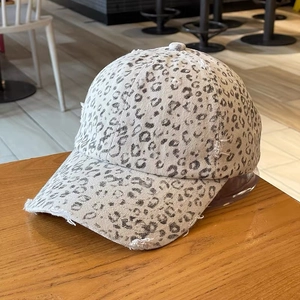 Close-up of leopard print baseball cap with distressed frayed edges on wooden table