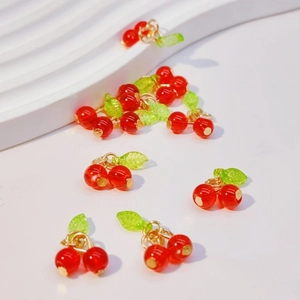 Macro view of red cherry fruit charms with green leaves and golden metal loops