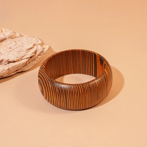 Macro view of a wide wooden bangle featuring zebra-patterned grain with polished finish