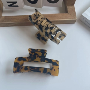 Detail view of two medium acetate hair claws in retro tortoiseshell patterns on a desk