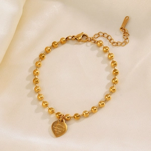Polished gold stainless steel bead bracelet with heart pendant on soft satin background