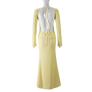 Détail d'une robe longue en maille jaune clair avec dos nu et lacets décoratifs