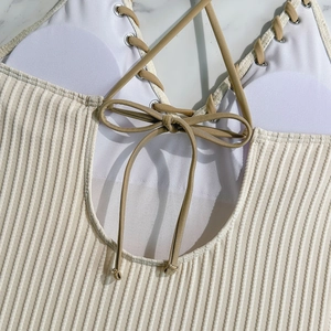 Macro detail of ribbed beige swimwear fabric with metal eyelets and lace-up design